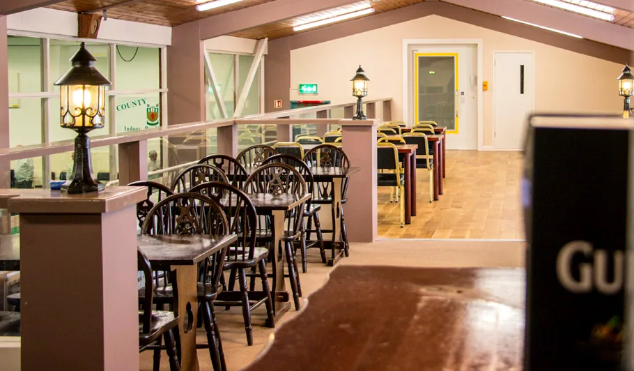 The bar, with tables and chairs behind a rail carrying the club crest
