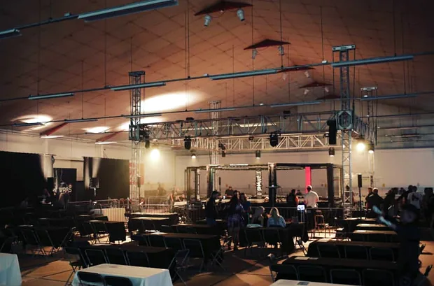 The hall dressed for a fight night: lighting truss rigged over the octagon, with tables and seating set out around it
