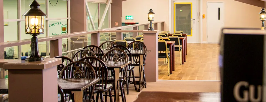 The Bar Lounge, tables and chairs behind a rail carrying the club crest