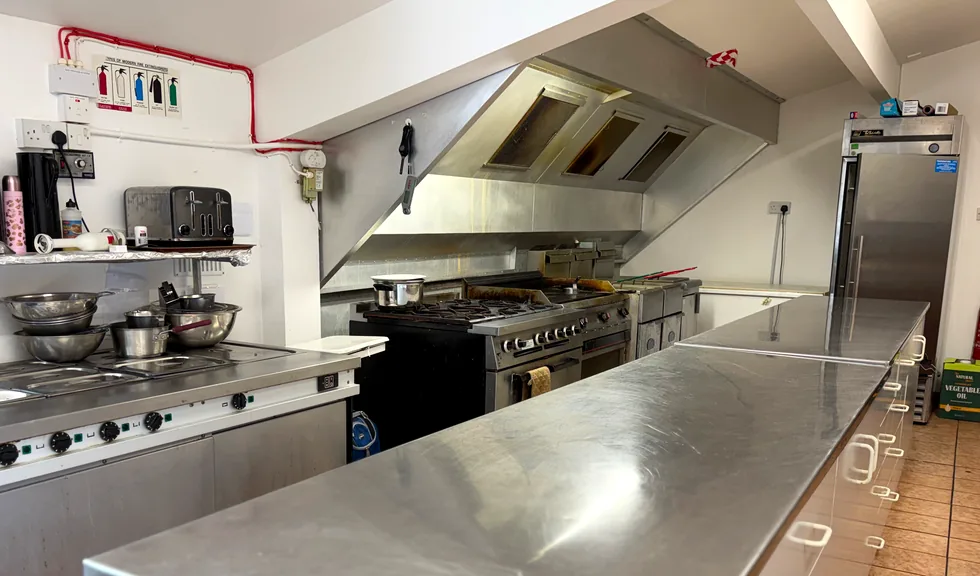 The club kitchen: a range under an extraction hood beside a long steel counter