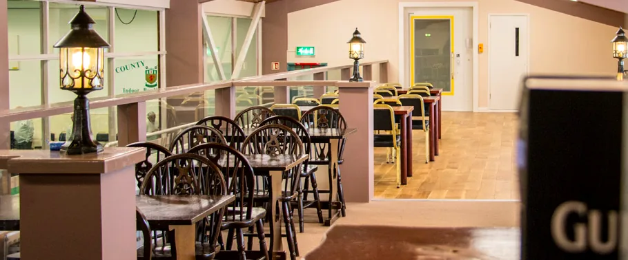 The Bar Lounge, with tables and chairs behind a rail carrying the club crest